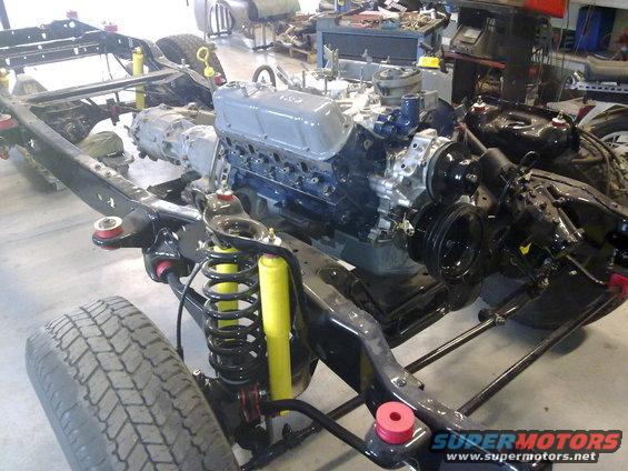 1984 Ford Bronco chassis with blue engine, grey valve covers, and yellow shocks