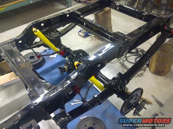 Black vehicle chassis with yellow shock absorbers during rebuild
