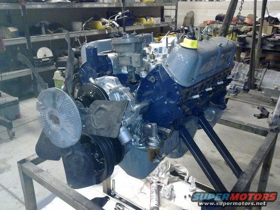 Ford V8 engine with blue painted block and grey valve covers, mounted on a metal stand