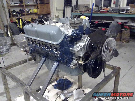 Engine on metal stand, painted blue and gray, with fan and pulleys attached