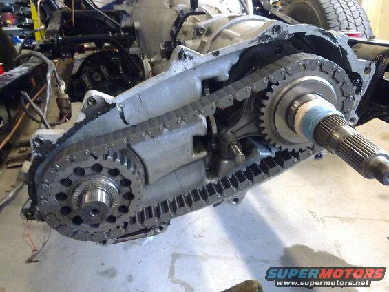 Transfer case assembly with chain and gears visible, part of a vehicle's drivetrain