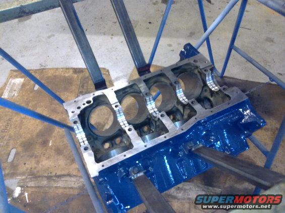 Blue engine block on stand with cylinder bores visible