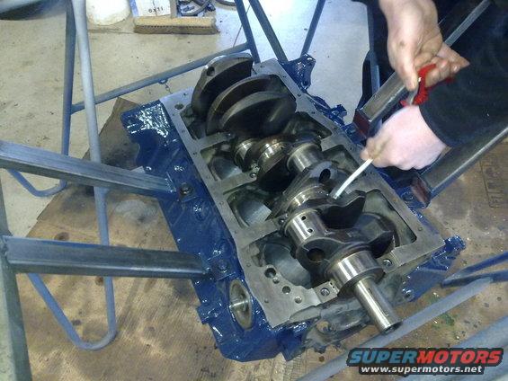 Engine block with crankshaft being worked on. Someone is cleaning or lubricating the crankshaft bearings