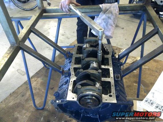 Engine block with crankshaft being worked on by a person with a torque wrench