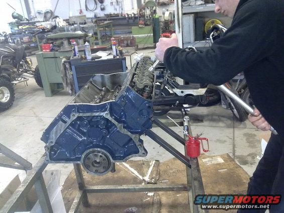 Blue engine block on stand with a person working on it