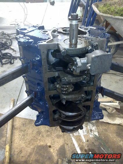 Engine block with crankshaft visible, mounted on metal supports