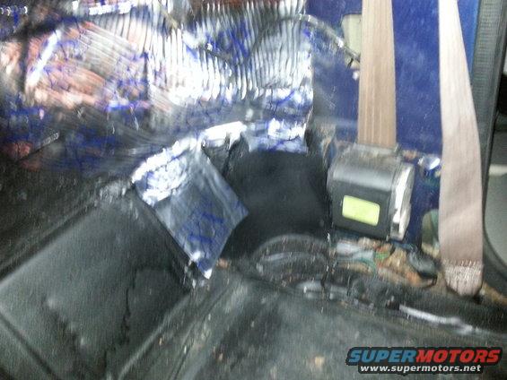 Interior view of vehicle with sound deadening material and seatbelt mechanism