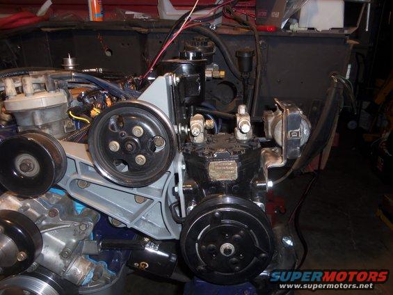 Close-up of engine parts including pulleys, compressor, and distributor