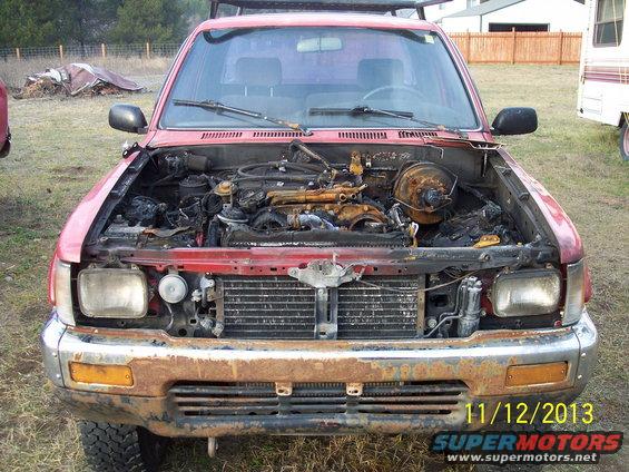 Red 1991 Toyota Pickup with open hood and damaged engine