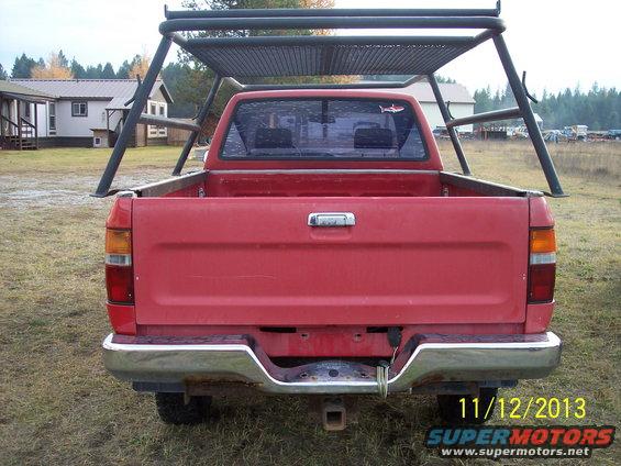 Red pickup truck rear view with a metal rack over the bed. Dated 11/12/2013