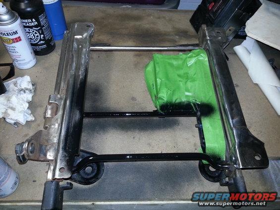 Seat frame with green tape on it, next to spray cans