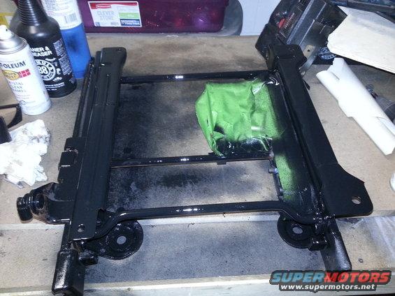 Black metal seat frame with green tape on a workbench