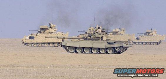 three military tanks driving in a desert landscape