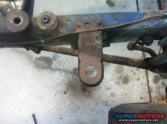 Rusty vehicle frame with a tow hook and suspension parts visible