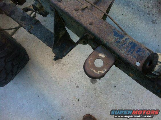 rusted vehicle frame section with suspension parts and a tire visible