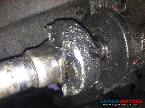 Damaged driveshaft universal joint covered in grease