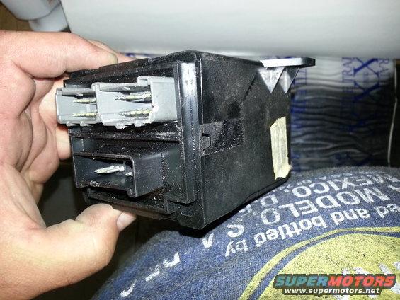 Black electrical part with gray connectors held by hand