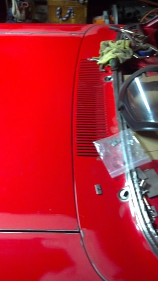 Red car fender with horizontal grille detail and a rag on top