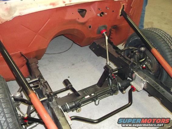 Front chassis and steering components of a car under construction. Supermotors.net logo visible