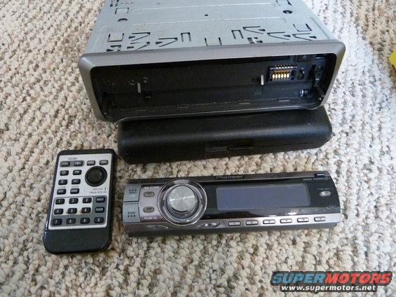Car stereo head unit, remote control, and mounting sleeve on carpet