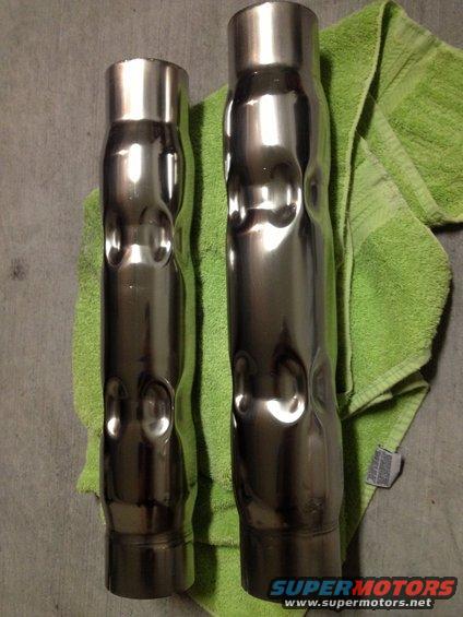 Two chrome exhaust pipes with dimpled sections, resting on a green towel