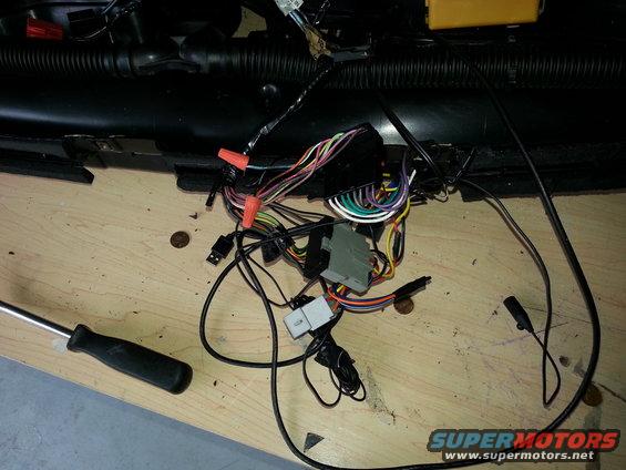 Car wiring harness with orange wire nuts and gray connector on a wooden surface