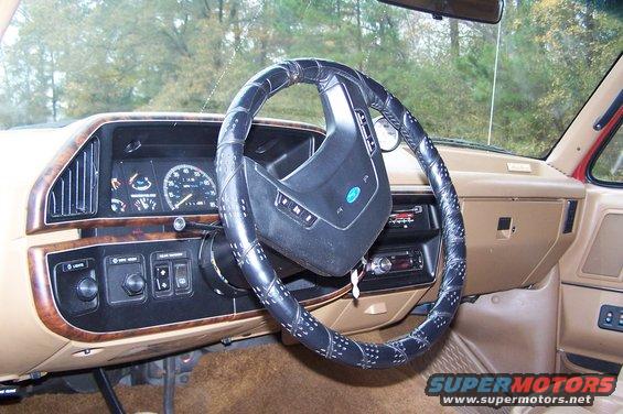 1990 Ford Bronco interior with tan dashboard, black steering wheel cover, and analog gauges