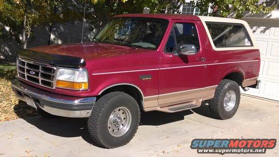 Red 1995 Ford Bronco with tan lower body trim and a white removable top, parked in a driveway