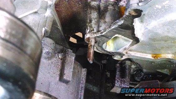 Close-up of engine component with visible oil leaks and rust
