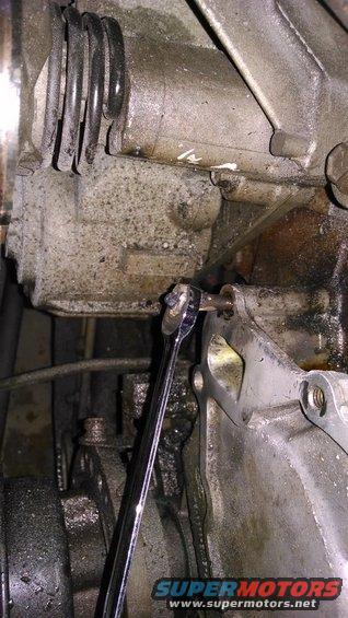 wrench turning bolt on greasy engine block
