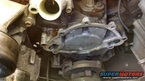 Engine water pump assembly with gasket removed, showing mounting holes and fluid residue