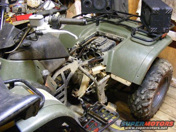 Olive green ATV with exposed engine and speakers mounted on rack