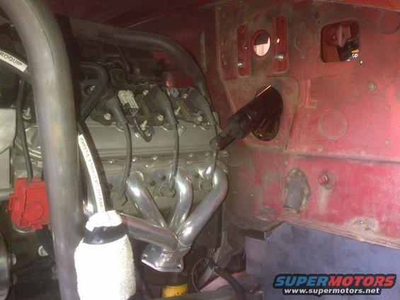Engine bay showing exhaust manifold and wiring. Text on a hose reads "GHESY6.9 75mm 150 PSI"