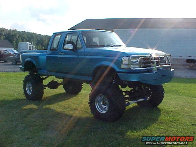 Lifted blue 1992 Ford F-150 pickup truck with large tires and custom grille guard