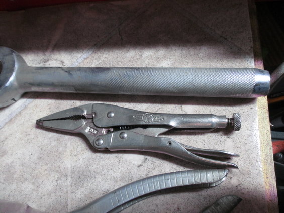 Large adjustable wrench and locking pliers on a textured surface