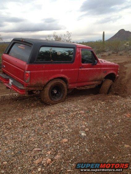 Red 1996 Ford Bronco stuck in mud, 3q-front view