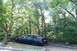 1993 Ford Taurus - A dark green sedan with black wheels is parked in a lot surrounded by trees.
