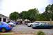 1993 Ford Taurus - Several cars are parked in a lot while a group of people stand and talk near them.