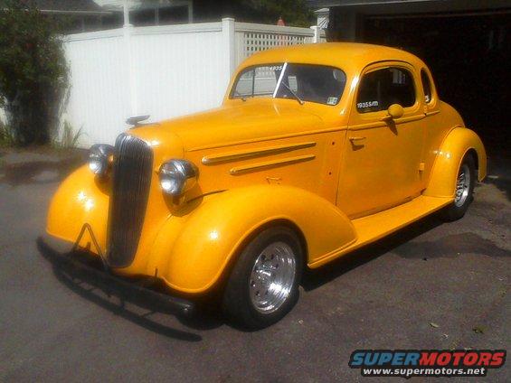 Yellow 1935 Chevrolet New coupe hot rod with custom wheels parked outside