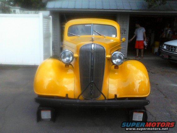 Yellow 1935 Chevrolet truck front view, parked in a driveway