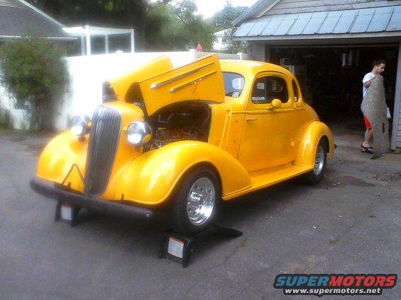 Yellow 1935 Chevrolet coupe with hood open, front 3/4 view