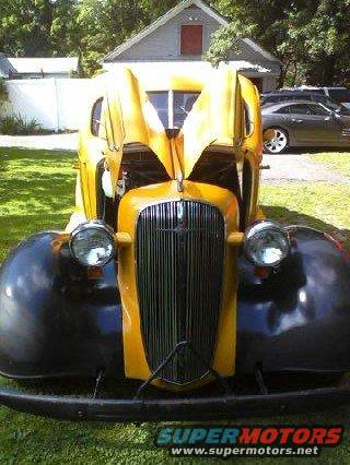 Yellow and black 1935 Chevrolet with hood open, front view