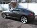 2004 Chrysler Crossfire - A gray Chrysler Crossfire coupe is parked in front of a white fence.