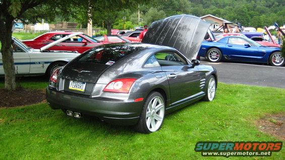 Gray Chrysler Crossfire with hood up, parked on grass next to other cars
