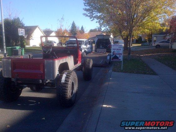 Red Jeep CJ-series with large tires, seen from rear