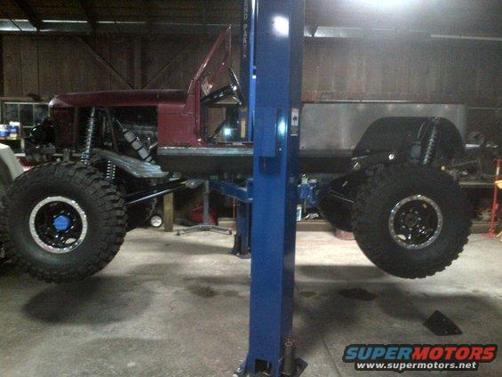 Customized off-road vehicle with large tires on a lift, side view