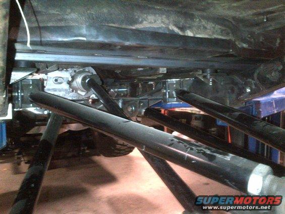 Underside of a vehicle on a lift, showing suspension and drivetrain components