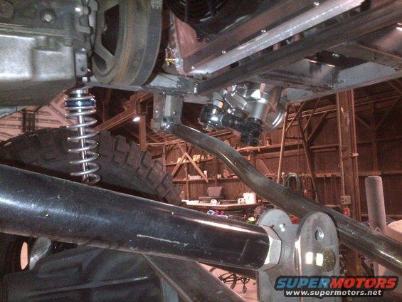 Undercarriage view of vehicle suspension and engine parts with Supermotors logo