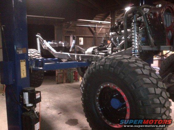 off-road vehicle frame on lift, large tires, roll cage visible