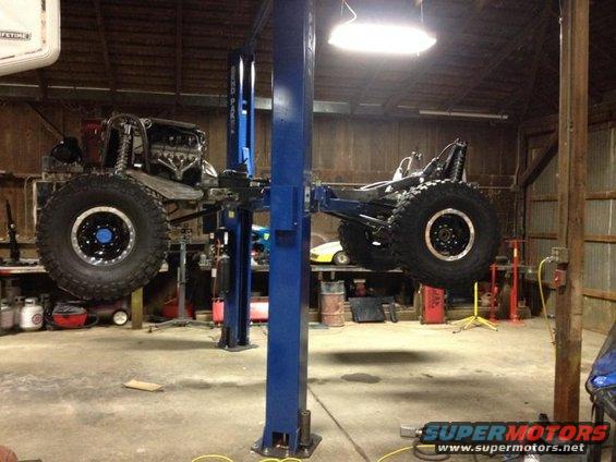 Off-road vehicle chassis on lift, showing engine and large tires